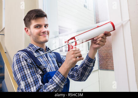 Arbeitnehmer Auftragen von Leim mit Silikon Pistole Stockfoto