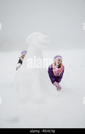 Kleine Mädchen im Winter Aufbau einer Abbildung der Hund von Schnee Stockfoto