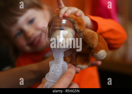 Glückliches Kind macht Inhalation zu Hause für Stockfoto