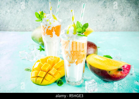 Tropische süßes Dessert Getränke. mango Milchshake oder Smoothie Cocktail, mit Mango Slices, Minze und Eiswürfel, hellblauer Hintergrund Kopie Raum Stockfoto