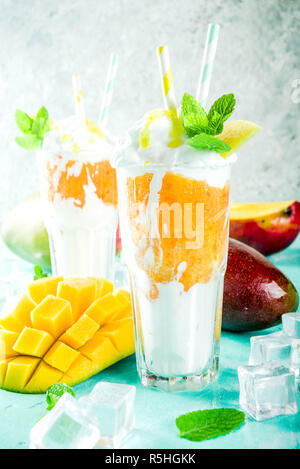 Tropische süßes Dessert Getränke. mango Milchshake oder Smoothie Cocktail, mit Mango Slices, Minze und Eiswürfel, hellblauer Hintergrund Kopie Raum Stockfoto