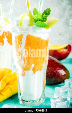 Tropische süßes Dessert Getränke. mango Milchshake oder Smoothie Cocktail, mit Mango Slices, Minze und Eiswürfel, hellblauer Hintergrund Kopie Raum Stockfoto
