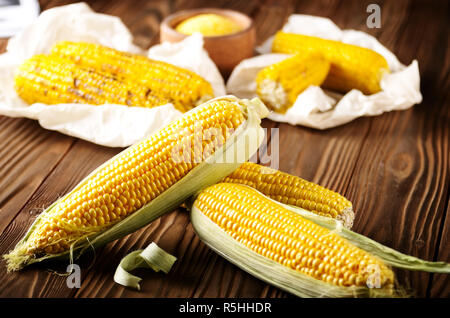 Küche Tisch mit Raw und gegrillter Zuckermais cob auf Backpapier und Grütze in Houten Stockfoto