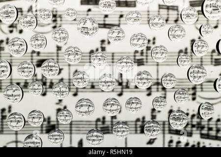 Musikalische Notation in Tropfen Wasser auf einem Hintergrund von verschwommenes Bild von Notizen Stockfoto