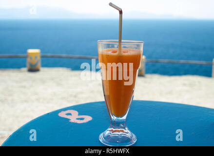 Ein Glas frischen Orangensaft mit Stroh auf einer Tabelle in einer Seaside Bar, Insel Kos, Griechenland Stockfoto