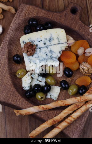 Blauschimmelkäse mit getrockneten Aprikosen und Oliven auf einen hölzernen Tisch Stockfoto