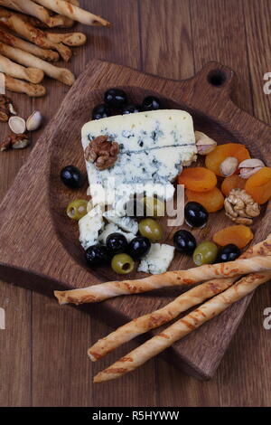 Blauschimmelkäse mit getrockneten Aprikosen und Oliven auf einen hölzernen Tisch Stockfoto