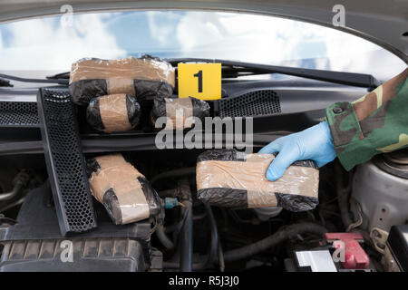 Polizist Medikament Paket entdeckt im Motorraum eines Autos Stockfoto