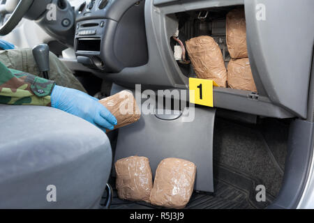 Polizeioffizier holding Droge Paket im Geheimfach in einem Auto gefunden Stockfoto