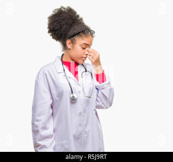 Junge afro-amerikanische Arzt Frau über isolierte Hintergrund Müde rieb Nase und Augen Gefühl der Müdigkeit und Kopfschmerzen. Stress und Frustration Konzept. Stockfoto