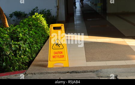 Closeup Bild der alten gelben Warnschild lesen Vorsicht nasser Boden, auf Gehweg von einem Gebäude, Sicherheitskonzept Stockfoto