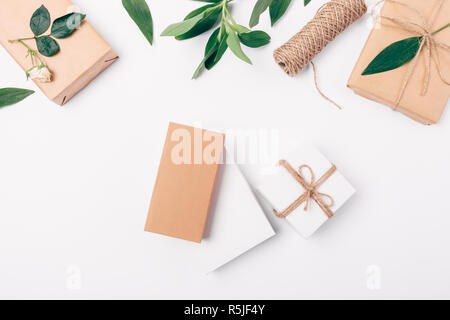 Flach Blumenschmuck der Geschenkboxen auf weißem Hintergrund, Ansicht von oben unter rose Blumen und grüne Blätter. Stockfoto