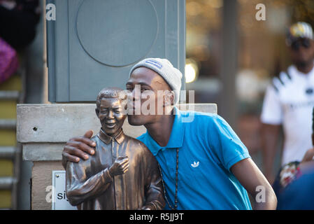 Johannesburg, Südafrika, 1. Dezember 2018. Ein Mann hat Freude daran, eine selfie mit einer Miniatur Nelson Mandela Statue, neben der größeren, in Nelson Mandela Square in Sandton. Südafrika ist derzeit die Feier des 100. Jahrestages der Madiba Geburt. Credit: Eva-Lotta Jansson/Alamy leben Nachrichten Stockfoto