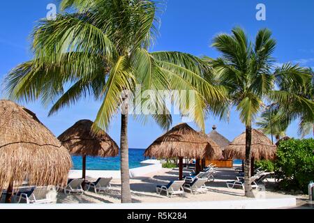 Palmen am weißen Sandstrand mit Liegen auf einer karibischen Insel. Stockfoto