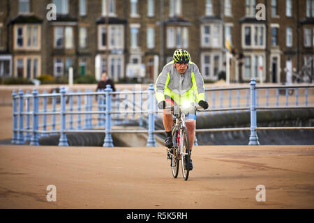 Am frühen Morgen eine cycalist OAP Radfahren entlang der Promenade Morecambe, Lancashire Stockfoto