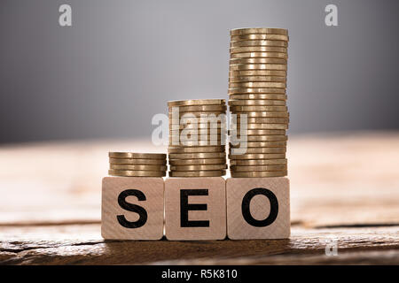 SEO Text auf Holzklötze mit gestapelten Münzen geschrieben Stockfoto