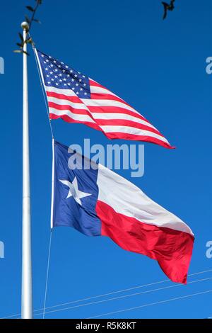 Ein Texas und eine amerikanische Flagge im Wind mit einem blauen Himmel im Hintergrund. Stockfoto
