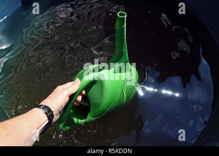 Regenwasser vom Regen Barrel. Eine Frau, die Bewässerung verwendet, kann Regenwasser aus der Regentonne zu bringen Stockfoto