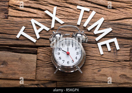 Steuer Zeit Text von Wecker auf hölzernen Tisch Stockfoto