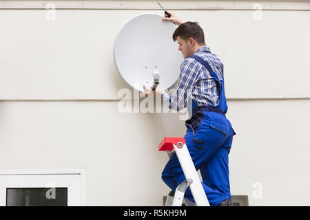 Techniker installieren TV Satellitenschüssel auf Wand Stockfoto