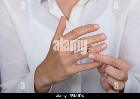 Frau Setzen auf ein glänzendes Gold Ring Stockfoto