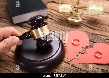 Richter schlagen Mallet durch gebrochene Herz aus Papier mit Ringen Stockfoto