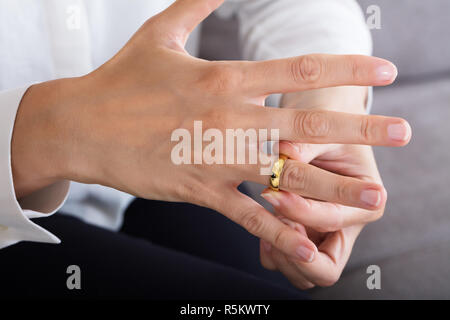 Frau Setzen auf ein glänzendes Gold Ring Stockfoto