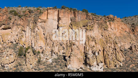 Panorama der stark texturierten, bunte hohe Klippen, Höhlen und Alten Indianischen Ruinen einer Cliff dwellings im Bandelier National Monument in der Nähe von San Stockfoto