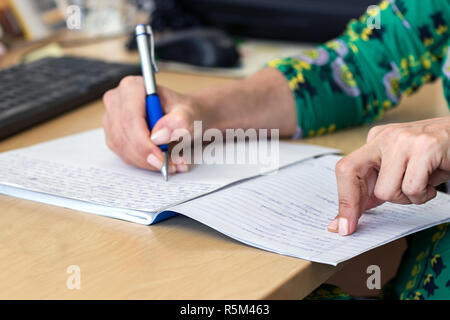 Weibliche hand Schreiben auf Papier - notebook auf dem Schreibtisch im Büro. Stockfoto