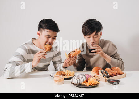 Zwei Freunde essen Burger. Pommes frites, Spaß haben und lächelnd Stockfoto