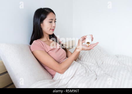 Frau Einnahme von Tabletten auf dem Bett Stockfoto