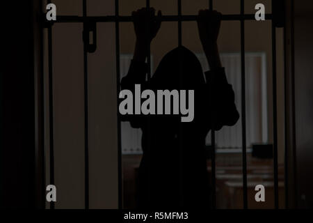 Der Gefangene hinter den Bars. mit den Händen auf die Gitter in der Verzweiflung. Stockfoto