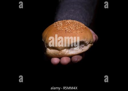 Armut Konzept. Die schmutzigen Hände Brot auf schwarzen Hintergrund. Stockfoto