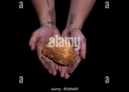 Armut Konzept. Hände halten Brot auf schwarzen Hintergrund. Stockfoto