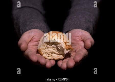 Armut Konzept. Händen Brot auf schwarzen Hintergrund. Stockfoto