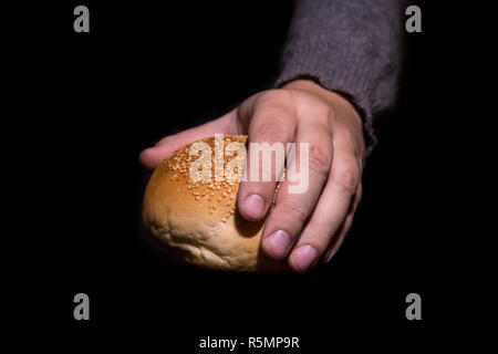 Armut Konzept. Händen Brot auf schwarzen Hintergrund. Stockfoto