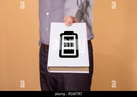 Mann hält ein Buch mit Batterie Symbol. Die Lebensdauer der Batterie. Stockfoto