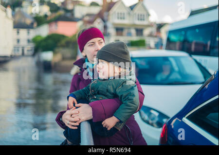 Eine junge Frau und ein kleines Kind über den Fluss im Winter auf eine Autofähre Stockfoto