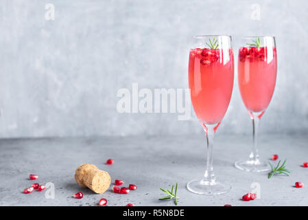 Granatapfel Champagner Mimosa Cocktail (mocktail) mit Rosmarin auf konkreten Hintergrund, kopieren. Mimosa Drink für Valentinstag oder anderen Feiertagen. Stockfoto