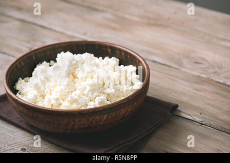 Der ökologische Landbau Hüttenkäse mit rustikalen Holzmöbeln Hintergrund, kopieren. Hausgemachte Hüttenkäse für gesunde Ernährung Lebensmittel. Stockfoto