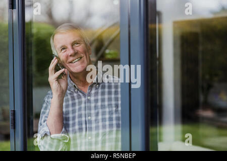 Ältere Menschen können Sie über das Telefon mit der Fenster Stockfoto