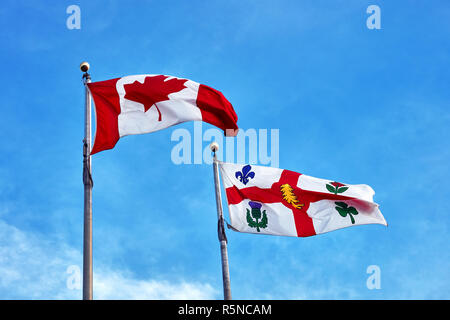 Kanadische Fahne und der Fahne von Montreal winken am klaren, blauen Himmel Hintergrund Stockfoto