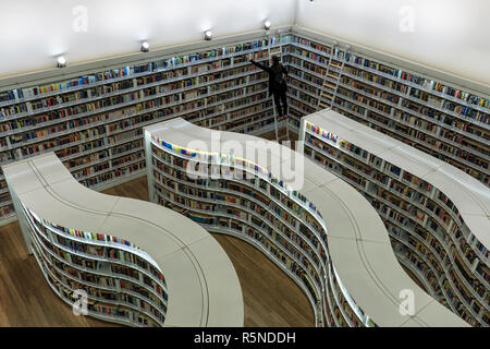 Singapur, Singapur - 17. Oktober 2018: Junge Frau ziehen Bücher aus der gebogenen Regalen der Bibliotheken an der Bibliothek an der Orchard Mall Stockfoto