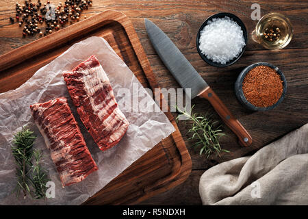 Raw Kalb skirt Steak Fleisch auf weißem kochen Papier und Holz Schneidebrett. Mit Kräutern, Gewürzen und kochmesser eingerichtet. Ansicht von oben. Stockfoto