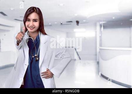 Hübsche asiatische Arzt lächelnd mit Krankenhaus Hintergrund Stockfoto