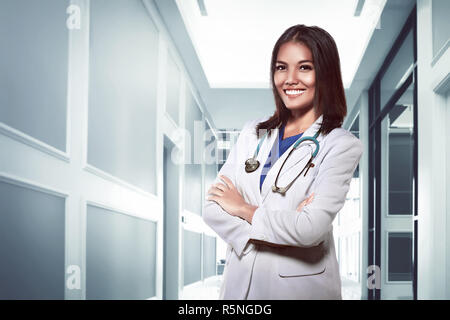 Hübsche asiatische Arzt lächelnd mit Krankenhaus Hintergrund Stockfoto