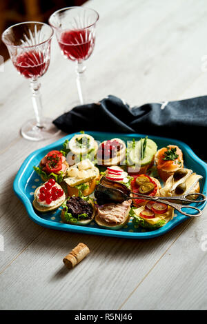 Set mini Sandwiches oder Tapas für Zwei mit Gläsern Wein auf hellem Holztisch Stockfoto