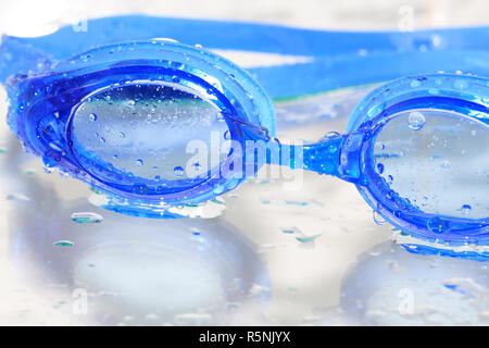 Nahaufnahme des blauen Nass Schwimmbrille auf Glas Hintergrund mit Wassertropfen Stockfoto