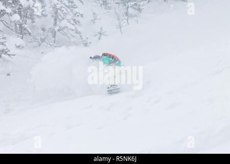 Mann, Snowboarder, Freerider geht auf Pulverschnee in den Bergen in einem Schneefall Stockfoto