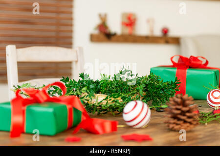 DIY Geschenkverpackung. Wunderschöne grüne Weihnachten Geschenke mit roter Schleife auf rustikalen Holztisch. Weihnachtsgeschenke verpacken Hintergrund. Stockfoto